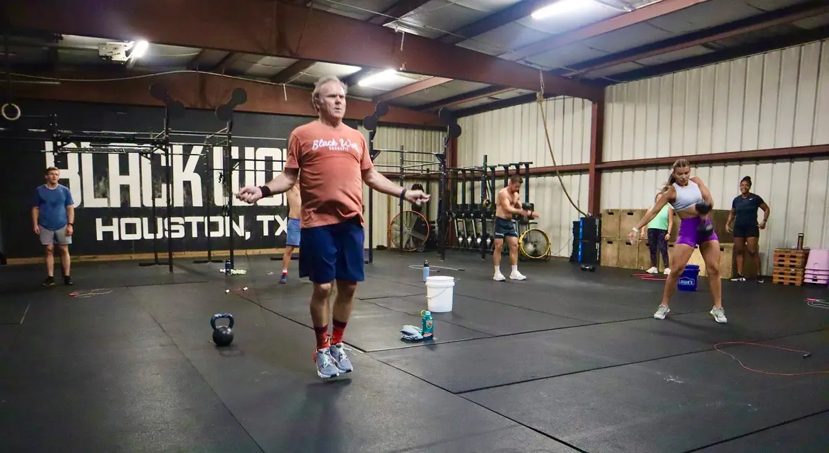 A Black Wolf coach leading class in front of the Black Wolf Houston wall